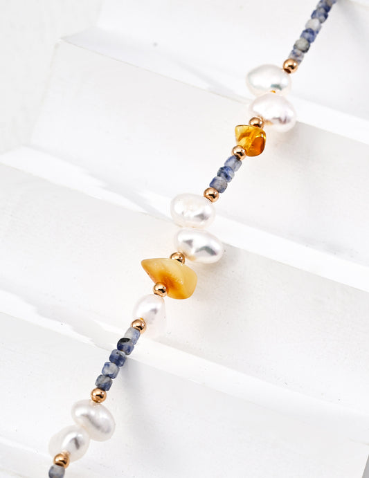 Close-up view of natural pearls, blue spotted stones, and beeswax amber accents, highlighting the intricate craftsmanship and unique design