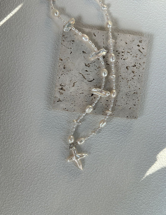 Distinctive necklace with a cross pendant, crafted from varying shapes of Baroque pearls, offering a unique and timeless design for all occasions.